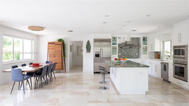 kitchen with glass insert cabinets, a center island, dark stone countertops, and built in appliances