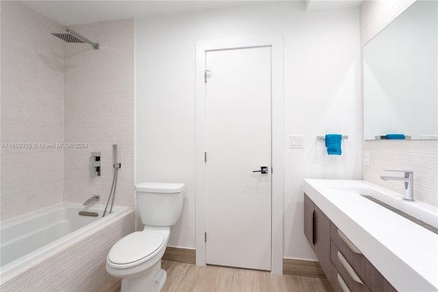 full bathroom featuring tiled shower / bath, vanity, hardwood / wood-style flooring, and toilet