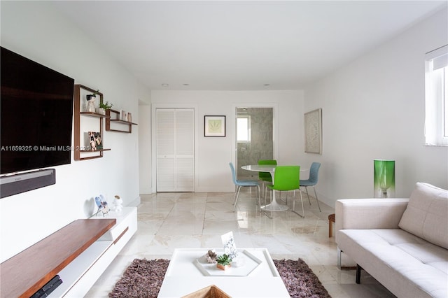 living room featuring a wealth of natural light, marble finish floor, and baseboards