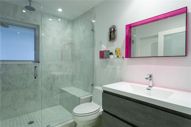 bathroom with vanity, a shower with shower door, and toilet