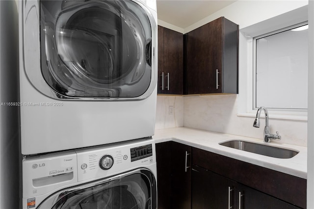 laundry area featuring cabinet space, a sink, and stacked washing maching and dryer