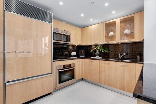 kitchen featuring dark stone counters, appliances with stainless steel finishes, sink, and light brown cabinets