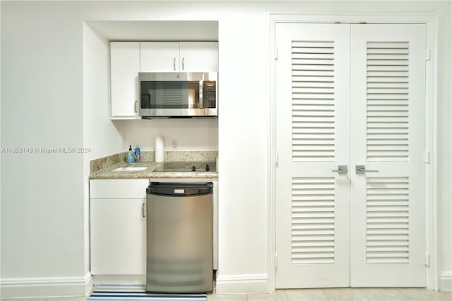 kitchen with white cabinetry, stainless steel appliances, and light tile patterned flooring