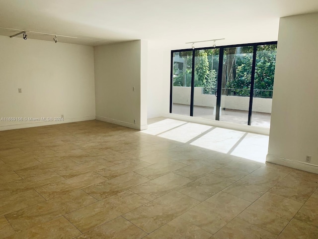 empty room featuring floor to ceiling windows and track lighting