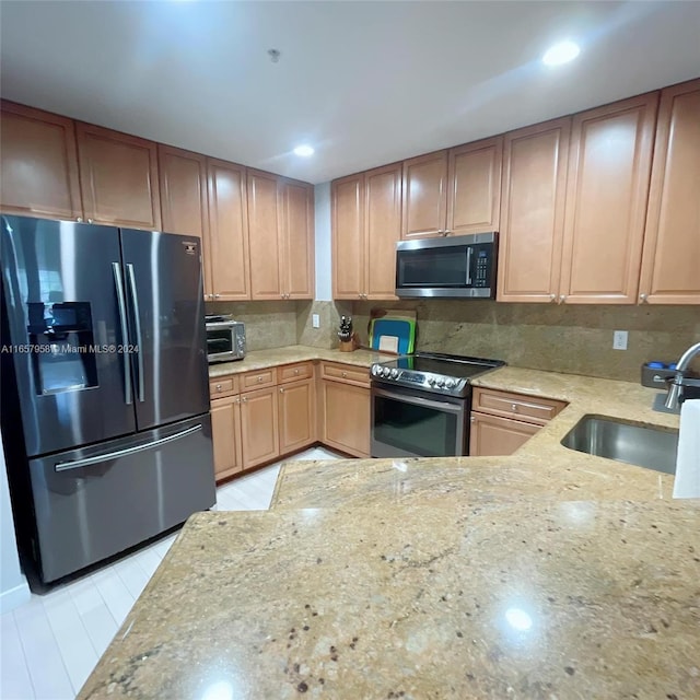 kitchen featuring light stone countertops, sink, decorative backsplash, and appliances with stainless steel finishes