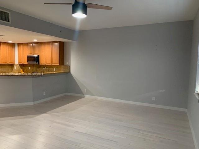 interior space featuring tasteful backsplash, light wood-type flooring, light brown cabinetry, and ceiling fan