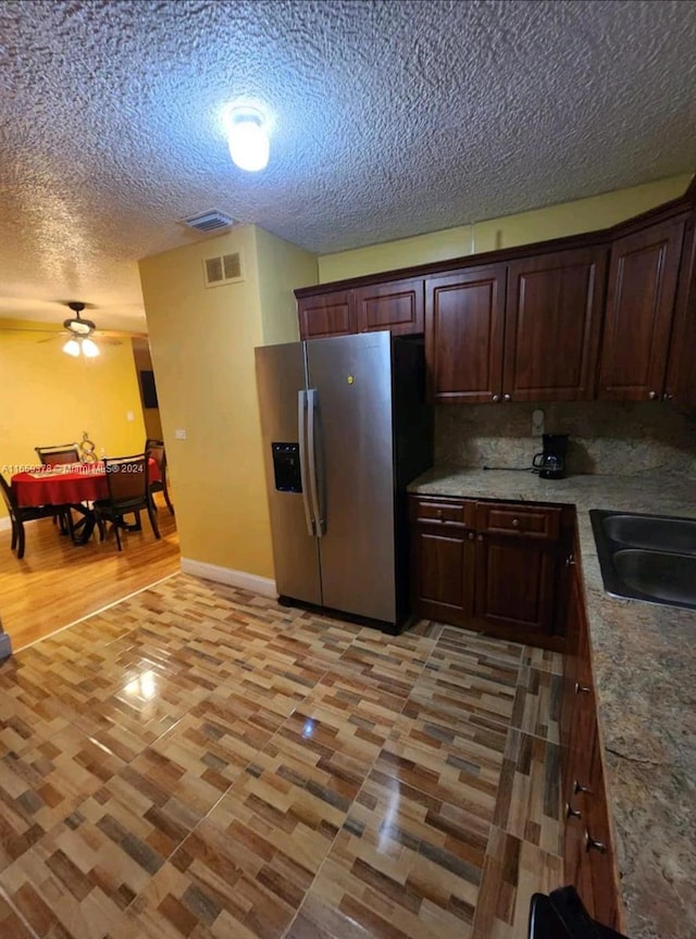 kitchen with stainless steel fridge, a textured ceiling, tasteful backsplash, ceiling fan, and light hardwood / wood-style floors