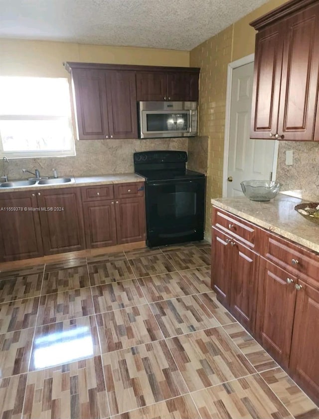 kitchen with black electric range, a textured ceiling, tasteful backsplash, and sink