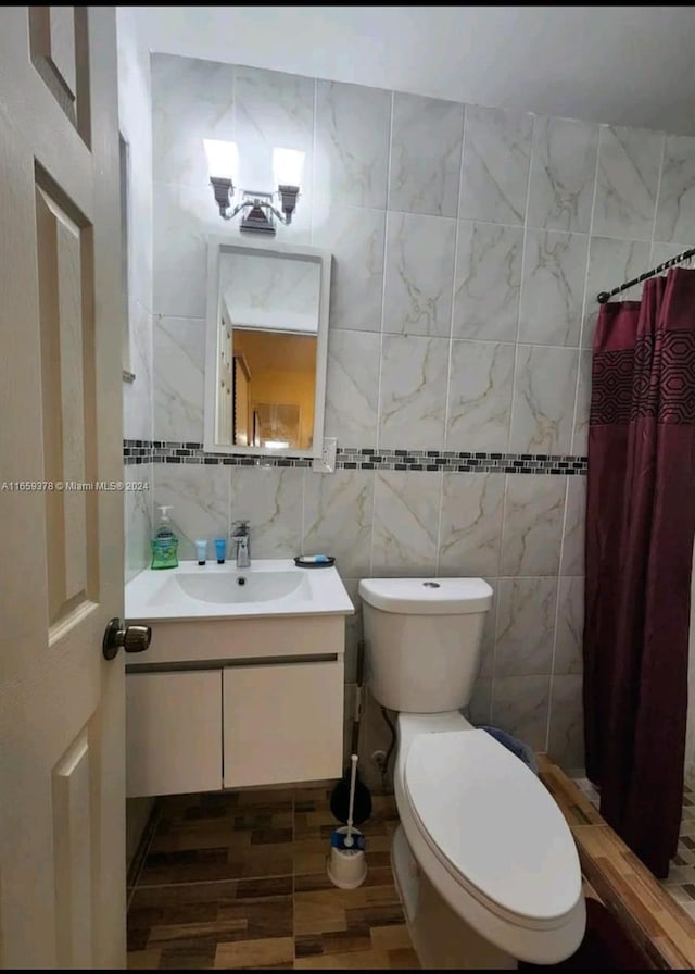 bathroom featuring vanity, toilet, curtained shower, and tile walls