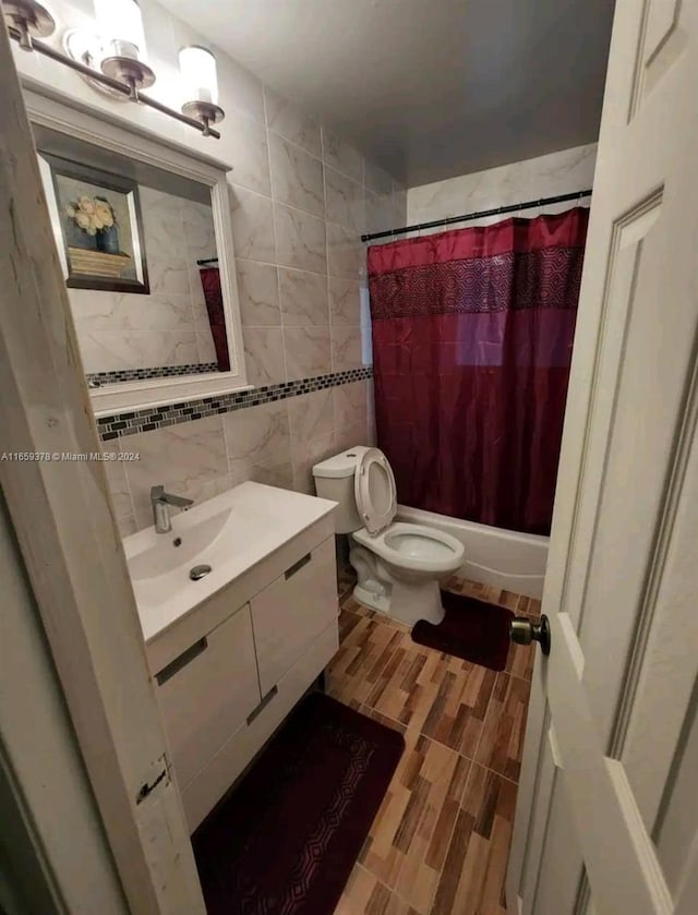 full bathroom featuring toilet, vanity, wood-type flooring, tile walls, and shower / tub combo with curtain