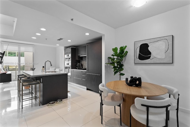 dining area featuring sink and light tile patterned floors