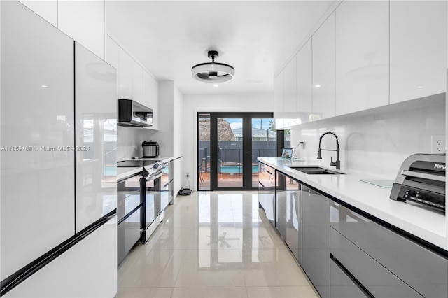 kitchen with appliances with stainless steel finishes, tasteful backsplash, sink, and white cabinets