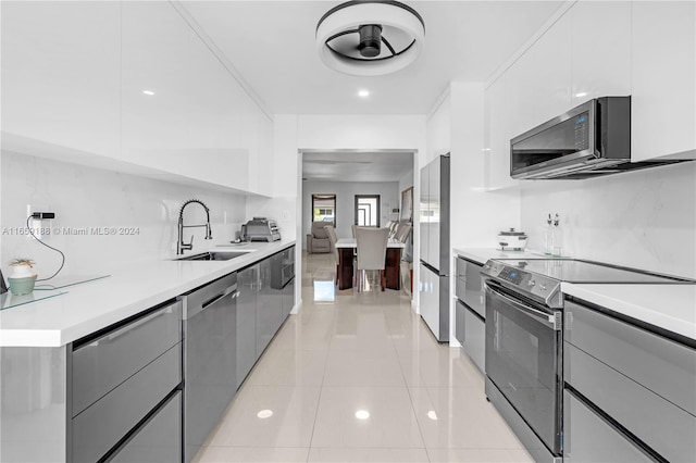 kitchen featuring white cabinets, stainless steel appliances, sink, ceiling fan, and light tile patterned flooring