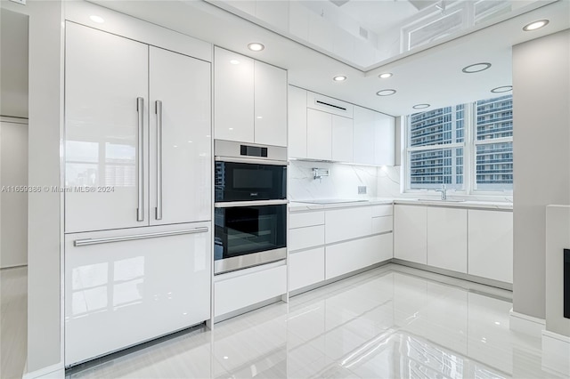 kitchen with white cabinets, paneled built in fridge, sink, decorative backsplash, and double oven