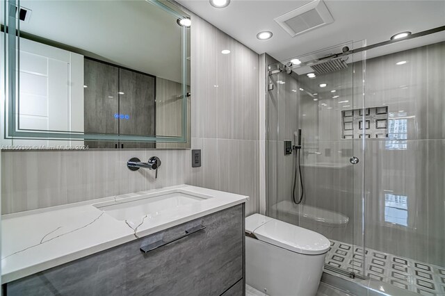 bathroom with vanity, toilet, walk in shower, and tile walls