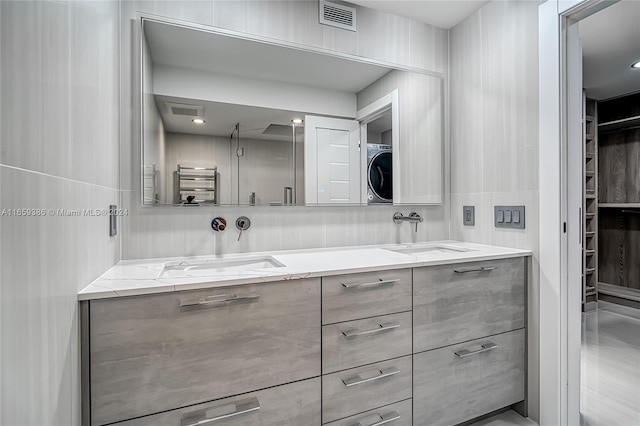 bathroom featuring vanity, radiator, and stacked washer / dryer