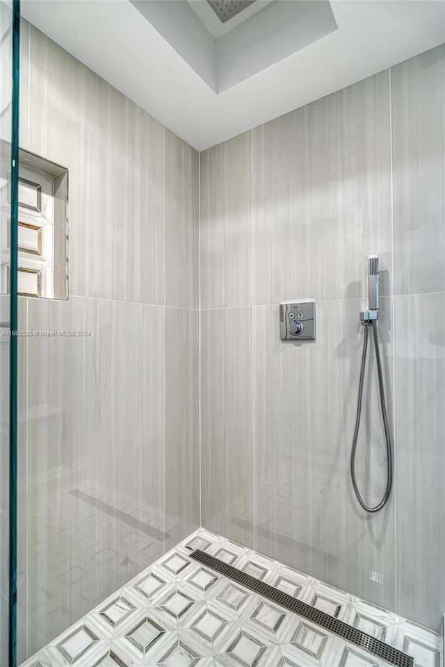 bathroom with a raised ceiling and a tile shower