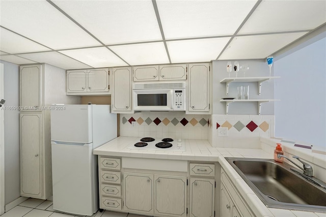 kitchen with white appliances, tasteful backsplash, sink, cream cabinets, and light tile patterned flooring