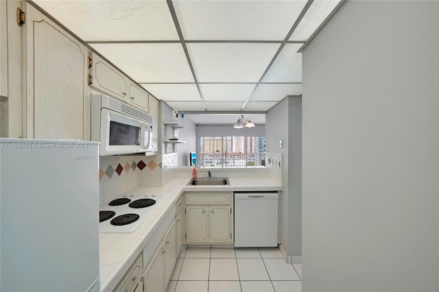 kitchen with white appliances, sink, a paneled ceiling, light tile patterned flooring, and decorative backsplash