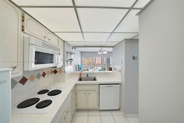 kitchen with white appliances, light tile patterned floors, sink, decorative backsplash, and a drop ceiling