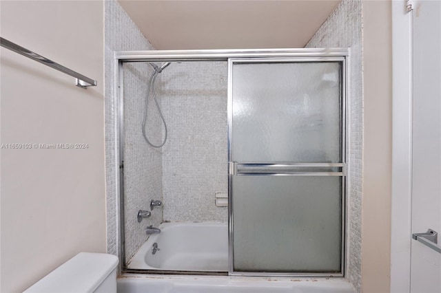 bathroom with toilet and bath / shower combo with glass door