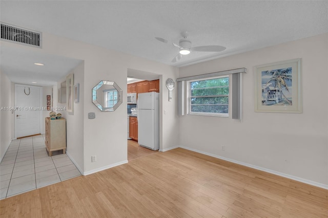 empty room featuring a textured ceiling, ceiling fan, and light wood-type flooring