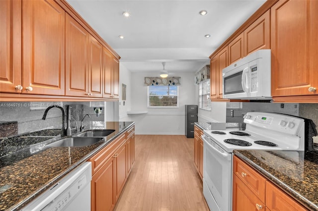 kitchen featuring dark stone counters, white appliances, light hardwood / wood-style flooring, and sink