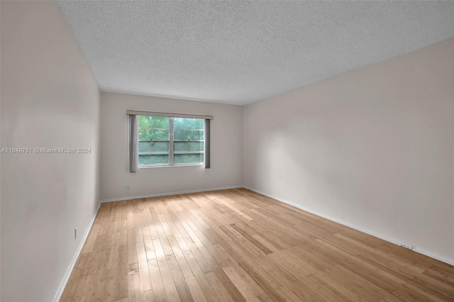 empty room featuring a textured ceiling and light hardwood / wood-style flooring