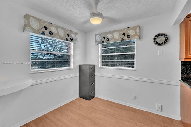 interior space with light wood-type flooring, a textured ceiling, and ceiling fan