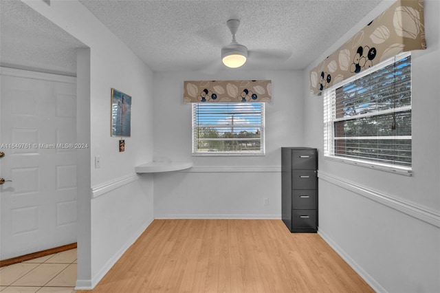 interior space with a textured ceiling, ceiling fan, and light hardwood / wood-style floors