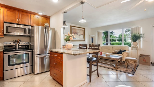 kitchen with light stone counters, pendant lighting, a breakfast bar, light tile patterned flooring, and appliances with stainless steel finishes