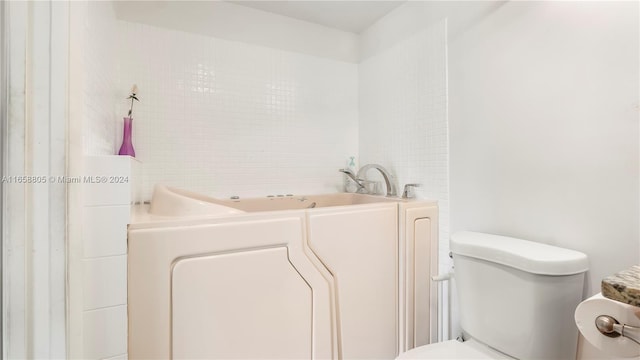 bathroom featuring toilet, a tub, and washer / clothes dryer