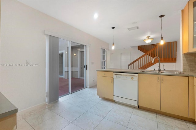 kitchen with dishwasher, pendant lighting, light brown cabinetry, and sink