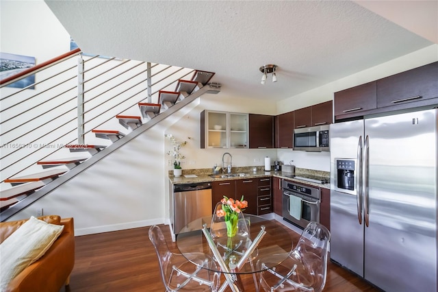 kitchen with sink, a textured ceiling, appliances with stainless steel finishes, dark brown cabinets, and dark hardwood / wood-style flooring