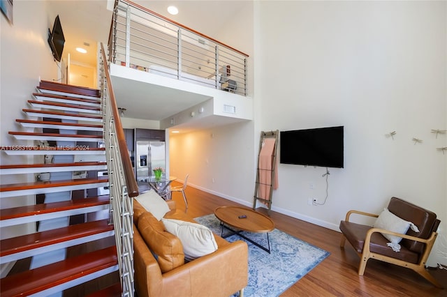 living room with hardwood / wood-style flooring and a towering ceiling