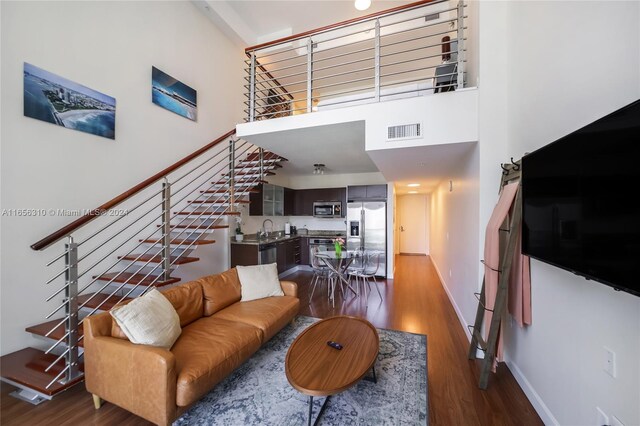 living room featuring sink, a towering ceiling, and dark hardwood / wood-style floors