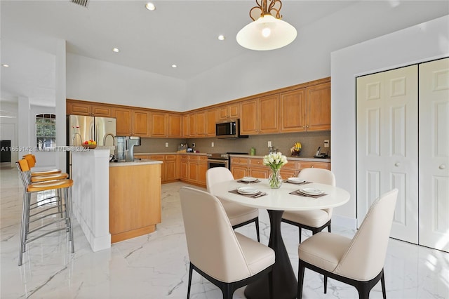 kitchen featuring tasteful backsplash, a kitchen island with sink, stainless steel appliances, and decorative light fixtures