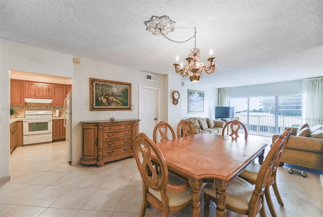 dining space with a textured ceiling, light tile patterned floors, and a chandelier