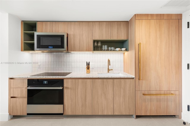 kitchen featuring light stone countertops, appliances with stainless steel finishes, tasteful backsplash, sink, and light brown cabinets