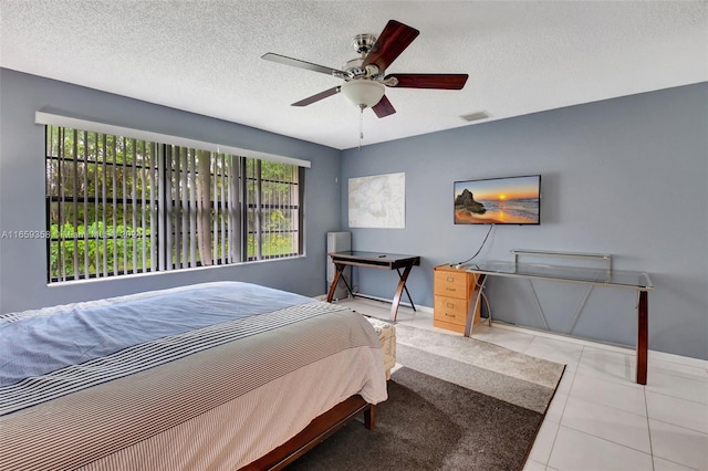 tiled bedroom with multiple windows, a textured ceiling, and ceiling fan