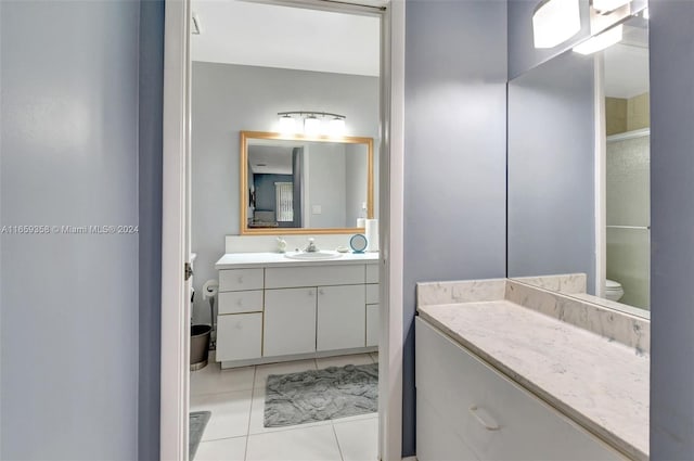 bathroom with a shower with door, vanity, toilet, and tile patterned flooring