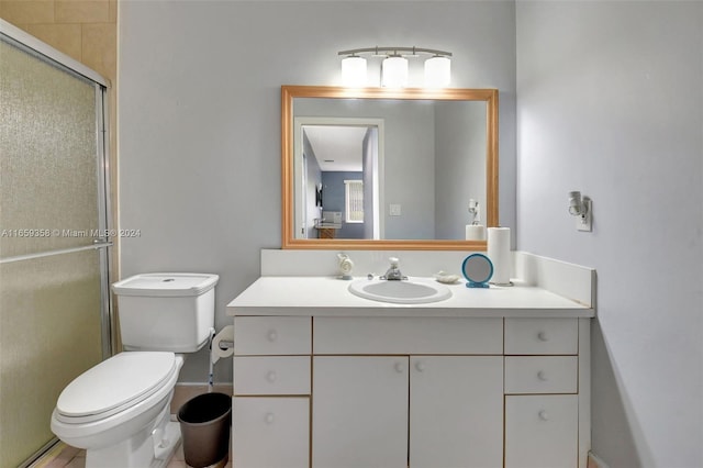 bathroom with toilet, a shower with shower door, and vanity