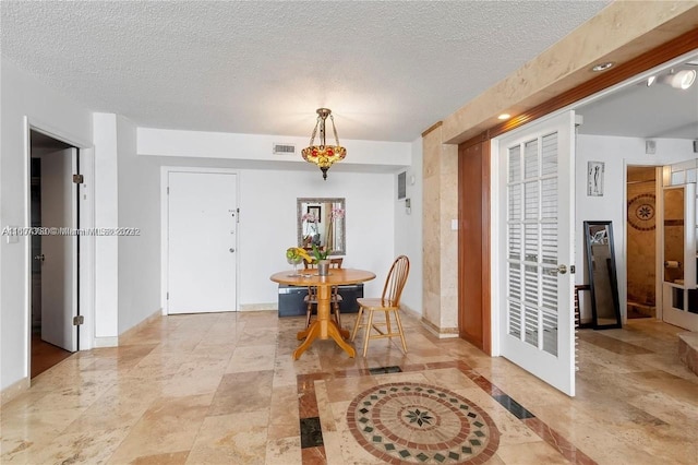 dining area with baseboards, a textured ceiling, and visible vents