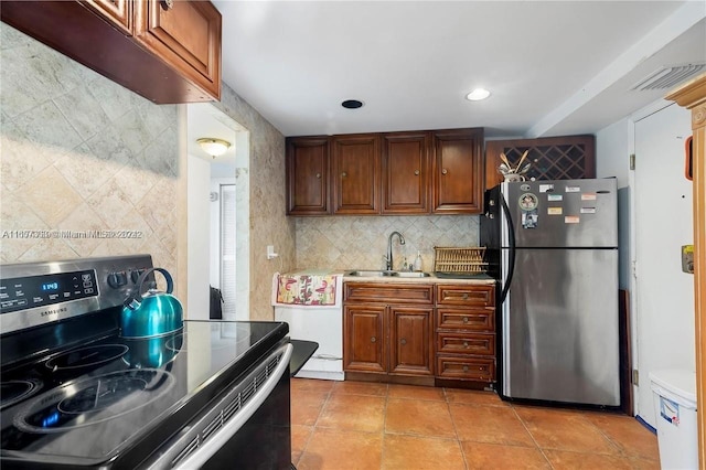 kitchen with light tile patterned flooring, appliances with stainless steel finishes, backsplash, and sink