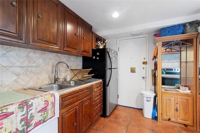 kitchen featuring backsplash, sink, light tile patterned floors, and stainless steel appliances