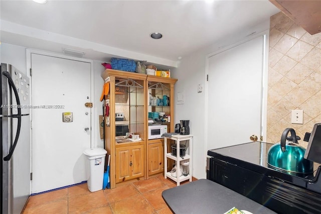 kitchen with light tile patterned flooring, freestanding refrigerator, and white microwave