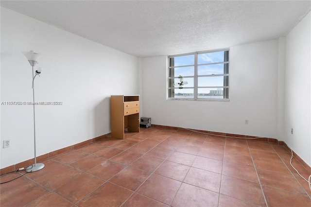 tiled empty room with a textured ceiling