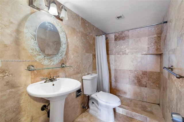 bathroom featuring walk in shower, tile walls, and toilet