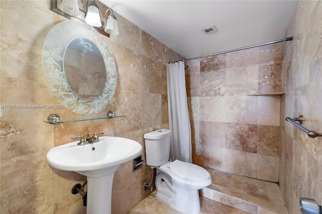 bathroom featuring tile walls, toilet, visible vents, and tiled shower