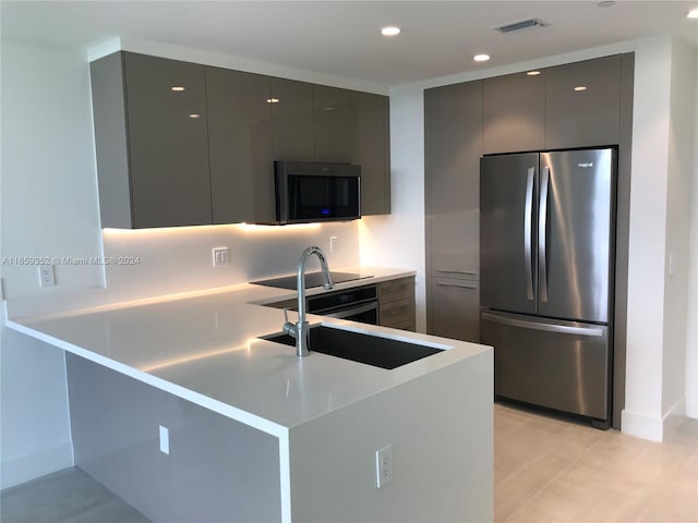 kitchen with gray cabinetry, stainless steel appliances, kitchen peninsula, and sink